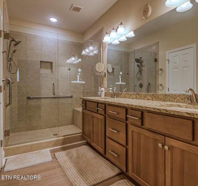 bathroom with hardwood / wood-style floors, vanity, and a shower with shower door