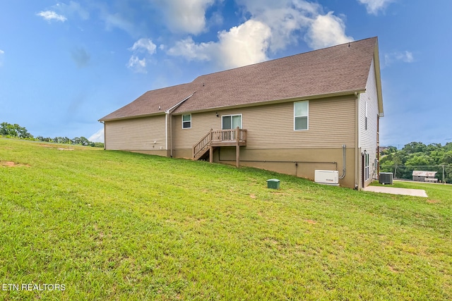 back of property with central air condition unit and a yard