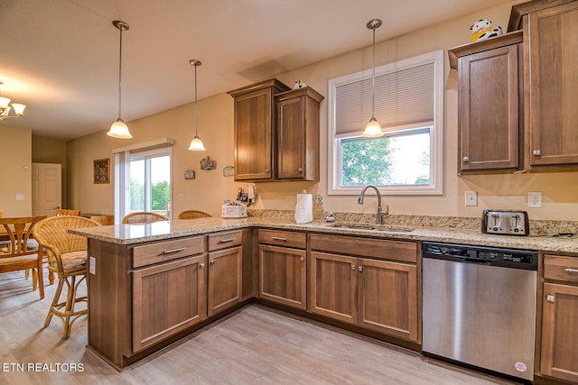 kitchen featuring sink, hanging light fixtures, light hardwood / wood-style flooring, stainless steel dishwasher, and kitchen peninsula