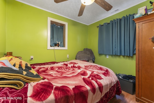 bedroom with hardwood / wood-style floors, ceiling fan, and ornamental molding