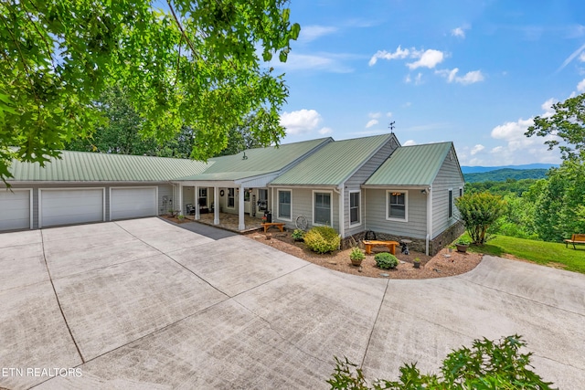 ranch-style home with covered porch, a mountain view, and a garage