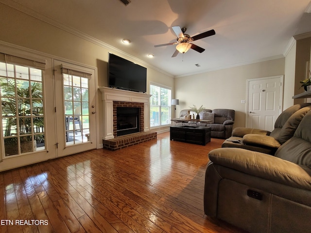 living room with ceiling fan, wood-type flooring, a fireplace, and ornamental molding