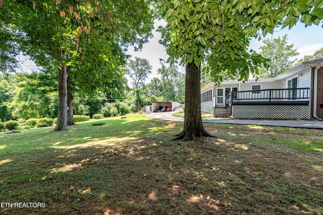 view of yard with a hot tub, a deck, and a sunroom