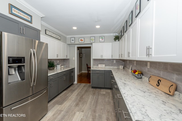 kitchen featuring stainless steel refrigerator with ice dispenser, light wood-type flooring, light stone counters, crown molding, and white cabinetry