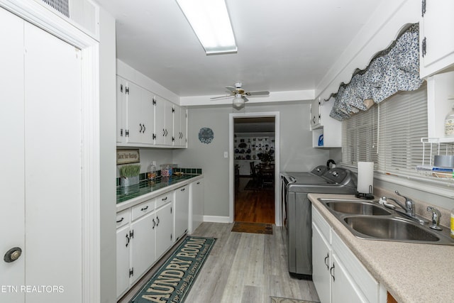 kitchen with washer and clothes dryer, white cabinets, sink, and light hardwood / wood-style flooring