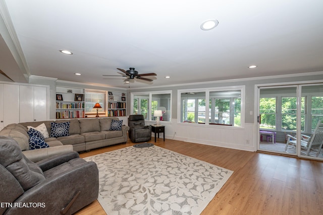 living room with ceiling fan, built in features, light wood-type flooring, and ornamental molding