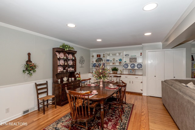 dining room featuring light wood-type flooring and crown molding