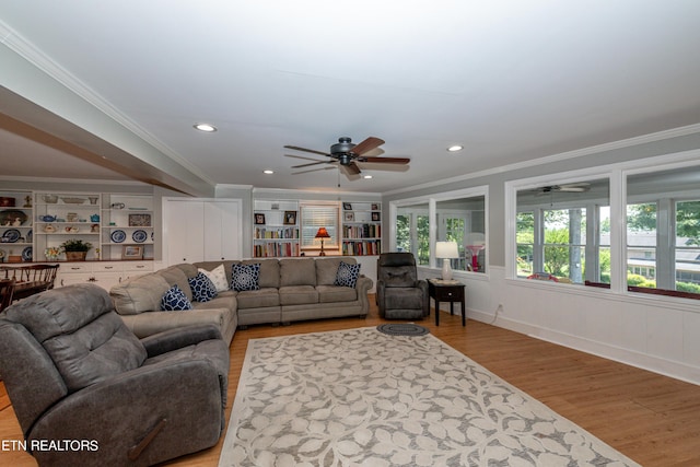 living room with built in shelves, light hardwood / wood-style flooring, and ornamental molding