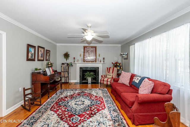 living room with ceiling fan, wood-type flooring, a premium fireplace, and ornamental molding