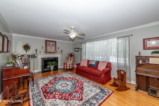 living room featuring wood-type flooring, ceiling fan, ornamental molding, and a premium fireplace