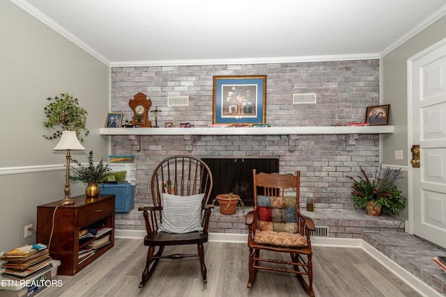 living area with a fireplace, light wood-type flooring, and ornamental molding