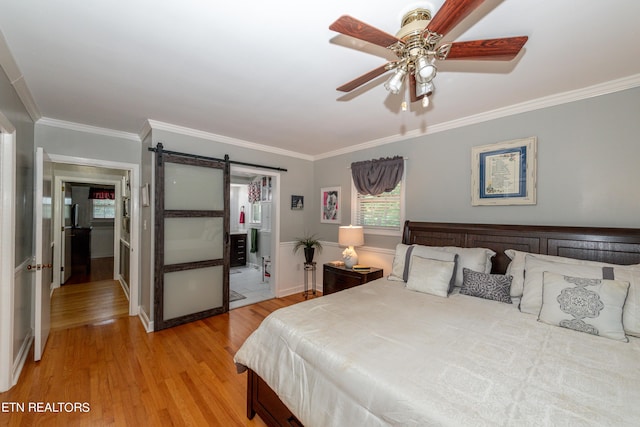 bedroom with a barn door, ceiling fan, light hardwood / wood-style floors, and ornamental molding