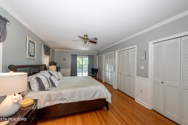 bedroom featuring multiple closets, ceiling fan, light hardwood / wood-style floors, and ornamental molding