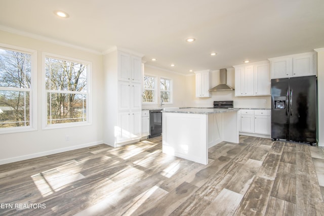 kitchen with black appliances, wall chimney range hood, white cabinetry, and a kitchen island