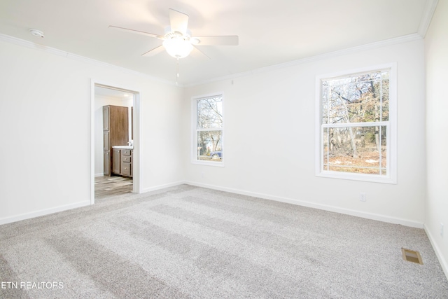 spare room featuring ceiling fan, light colored carpet, a wealth of natural light, and ornamental molding