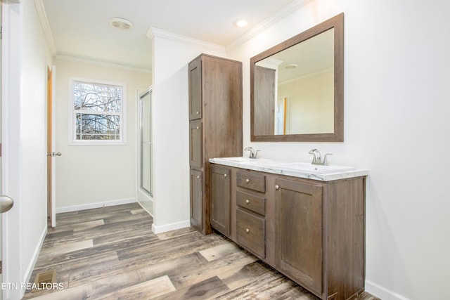 bathroom with ornamental molding, a shower with door, wood-type flooring, and vanity