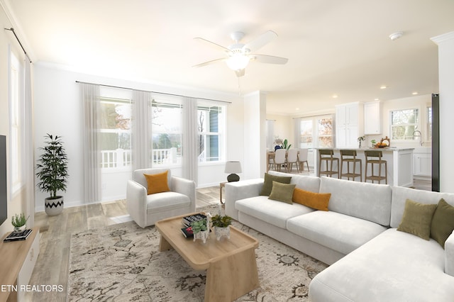 living room featuring ceiling fan, a healthy amount of sunlight, light wood-type flooring, and crown molding