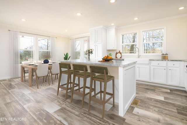 kitchen featuring ornamental molding, light hardwood / wood-style flooring, white cabinets, and a center island