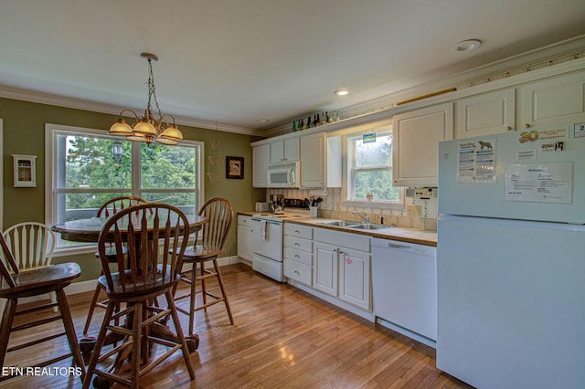 kitchen featuring an inviting chandelier, white cabinetry, white appliances, hanging light fixtures, and sink