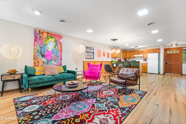 living room featuring an inviting chandelier and light wood-type flooring