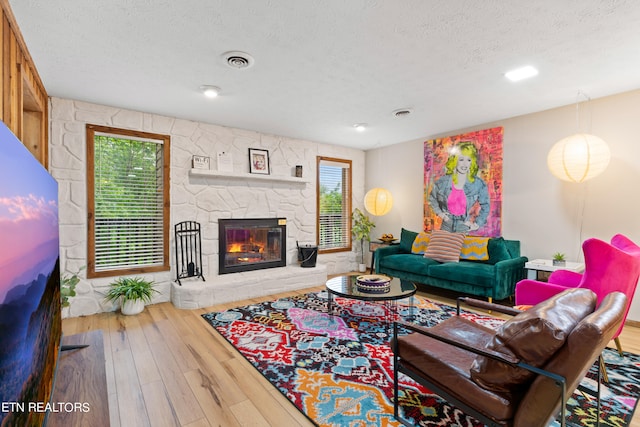 living room with hardwood / wood-style floors, a fireplace, and a textured ceiling