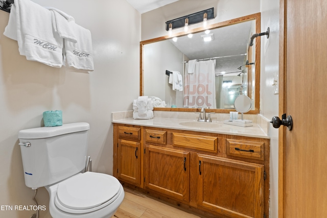 bathroom featuring hardwood / wood-style floors, vanity, a shower with shower curtain, and toilet