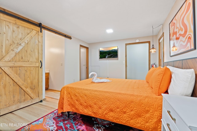 bedroom featuring a barn door and light wood-type flooring