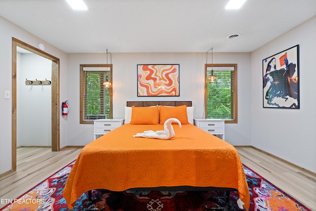 bedroom with light hardwood / wood-style floors and multiple windows