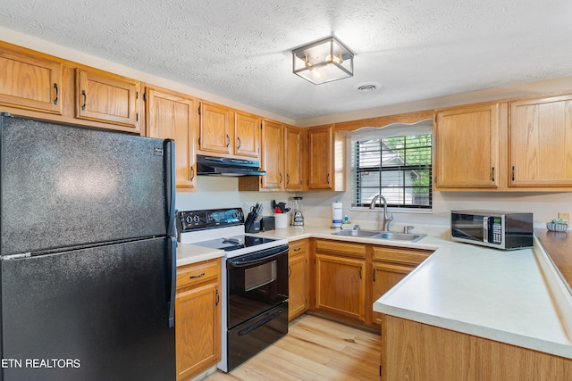 kitchen featuring black appliances, light hardwood / wood-style floors, sink, and a textured ceiling