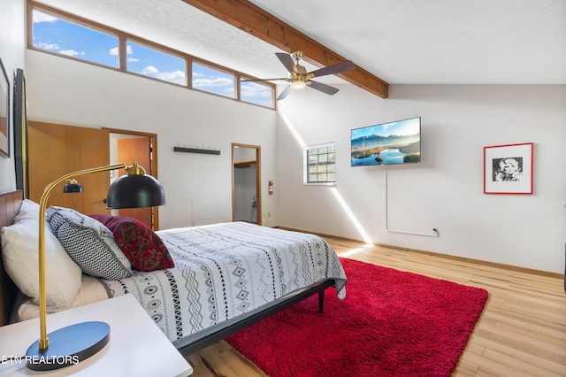 bedroom featuring multiple windows, vaulted ceiling with beams, hardwood / wood-style flooring, and ceiling fan