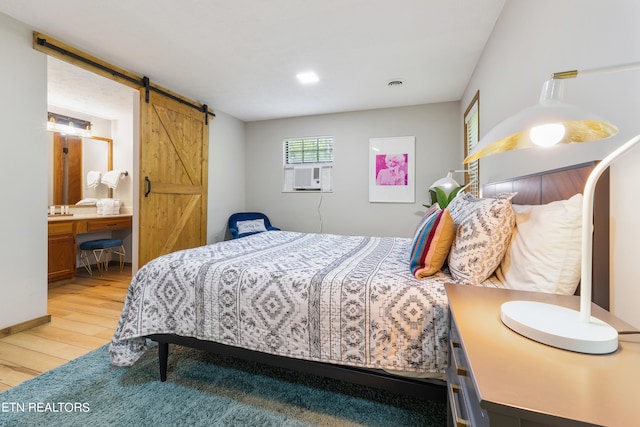 bedroom featuring a barn door, light hardwood / wood-style floors, and cooling unit