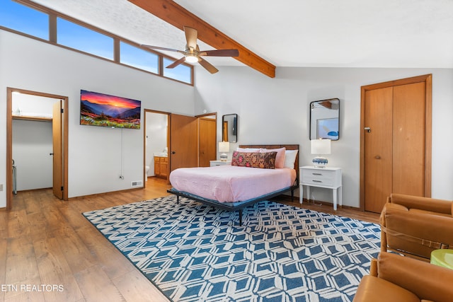 bedroom featuring connected bathroom, ceiling fan, vaulted ceiling with beams, and hardwood / wood-style flooring