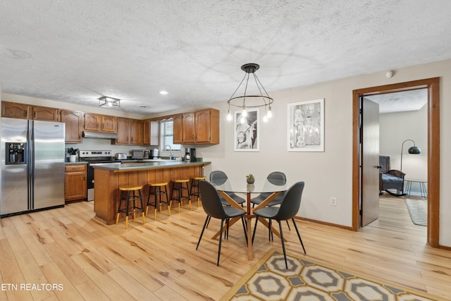 dining room featuring a textured ceiling and light hardwood / wood-style flooring