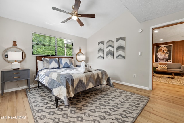 bedroom with ceiling fan, light hardwood / wood-style floors, lofted ceiling, and a textured ceiling