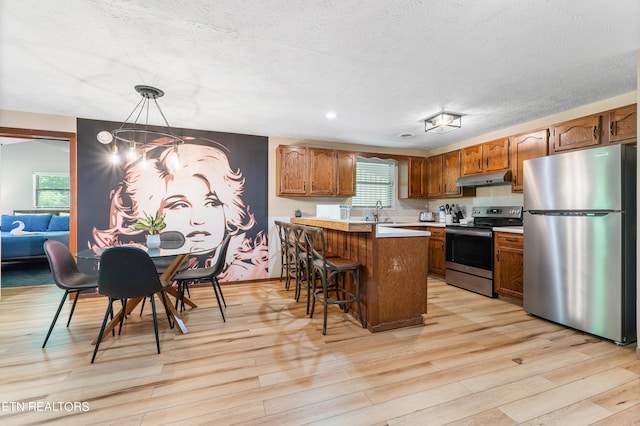 kitchen featuring stainless steel appliances, a kitchen breakfast bar, a chandelier, pendant lighting, and a kitchen island