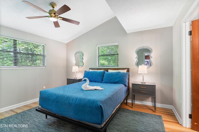 bedroom with ceiling fan, vaulted ceiling, and light wood-type flooring