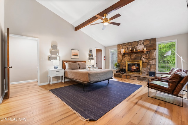 bedroom with multiple windows, a stone fireplace, and light hardwood / wood-style floors