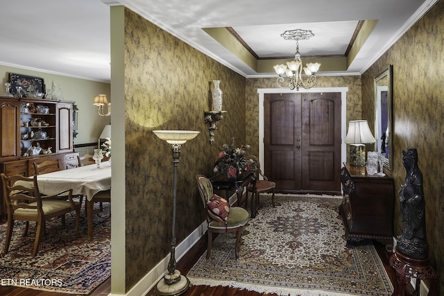 entrance foyer featuring a notable chandelier, crown molding, baseboards, and wood finished floors