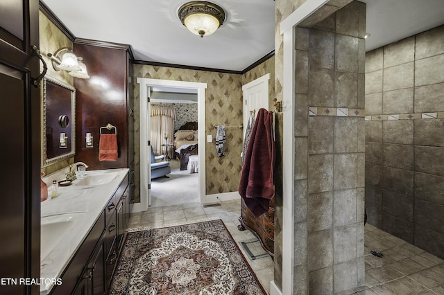 bathroom featuring baseboards, wallpapered walls, ensuite bath, a sink, and crown molding