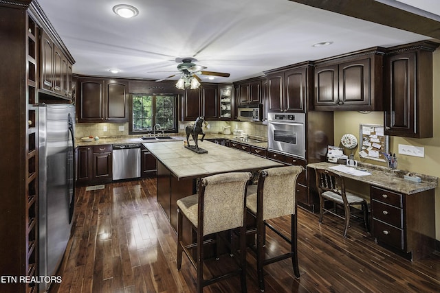 kitchen with dark brown cabinets, dark wood-type flooring, appliances with stainless steel finishes, and a sink