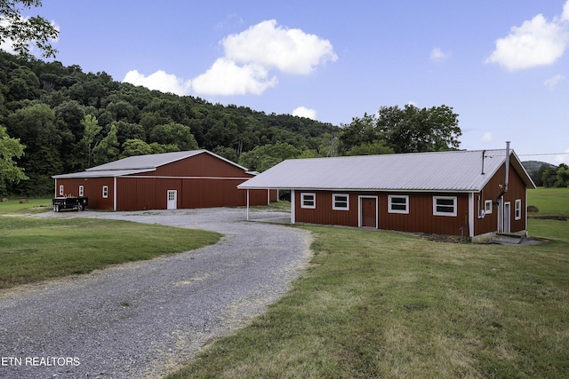 ranch-style house featuring driveway, an outdoor structure, a front yard, a pole building, and metal roof