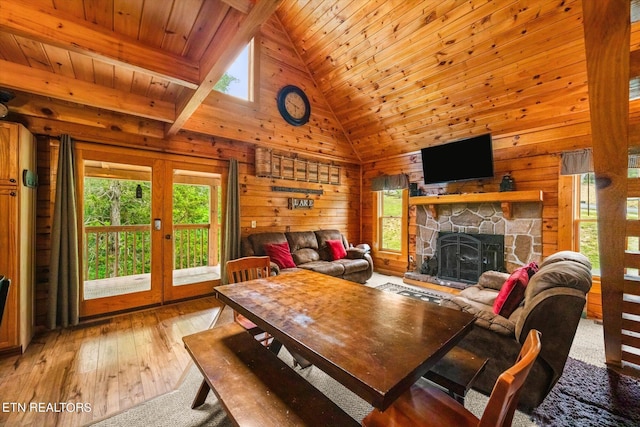 living room with a fireplace, wood walls, wood ceiling, plenty of natural light, and high vaulted ceiling