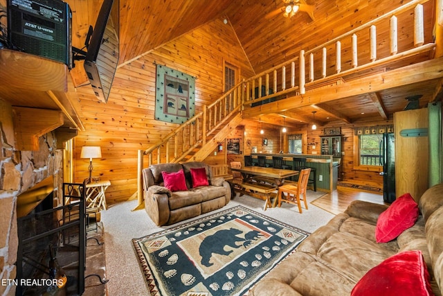 carpeted living room featuring lofted ceiling, ceiling fan, wooden walls, and wooden ceiling