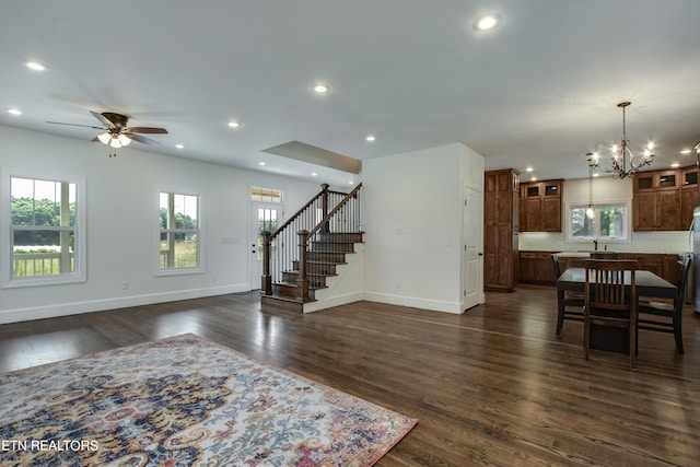 living room featuring dark hardwood / wood-style flooring and ceiling fan with notable chandelier