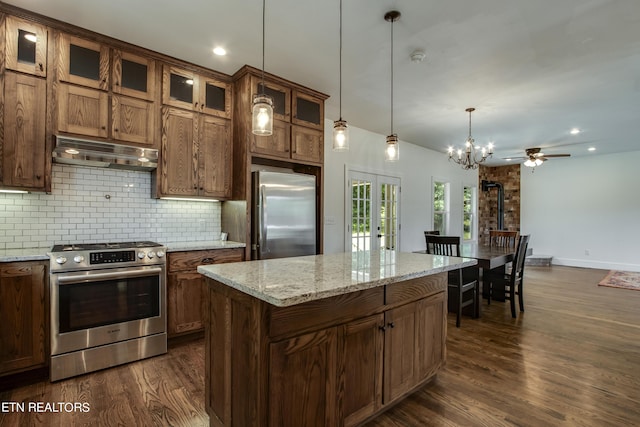 kitchen with appliances with stainless steel finishes, a center island, decorative light fixtures, decorative backsplash, and ceiling fan