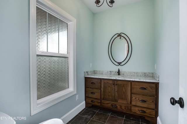 bathroom with toilet, vanity, and an inviting chandelier