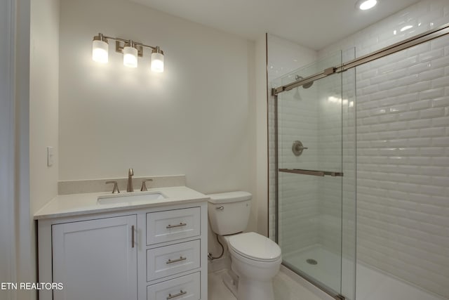 bathroom featuring a shower with door, toilet, and vanity