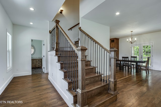 staircase featuring french doors, an inviting chandelier, and hardwood / wood-style flooring