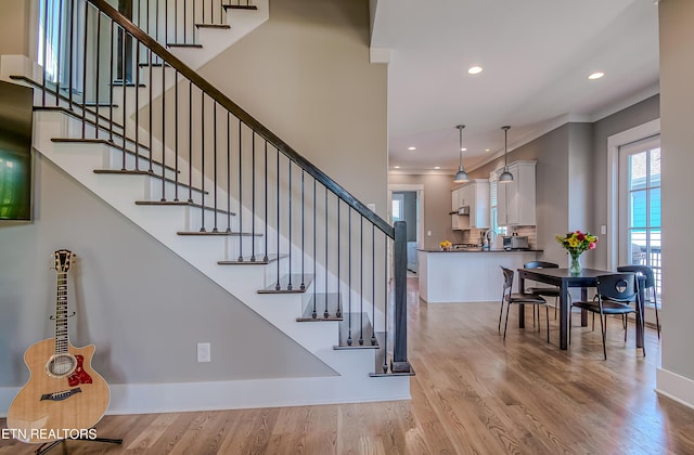 stairway with crown molding and hardwood / wood-style floors