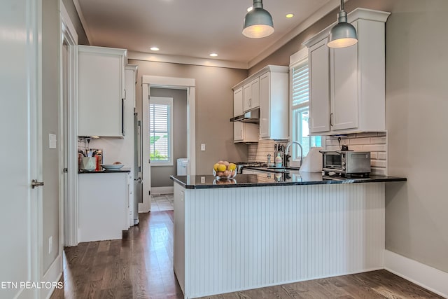 kitchen with hanging light fixtures, kitchen peninsula, dark hardwood / wood-style floors, decorative backsplash, and white cabinets